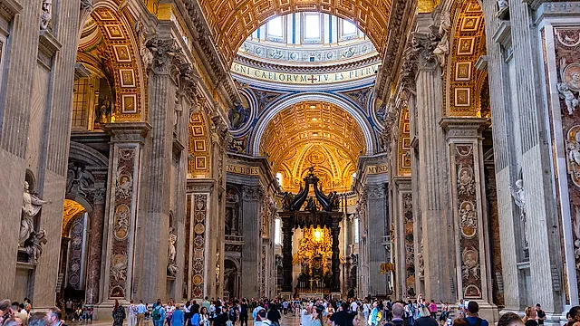 The central nave of St Peter's Basilica with its coffered barrel vault, marble pillars and the baldachin in the distance