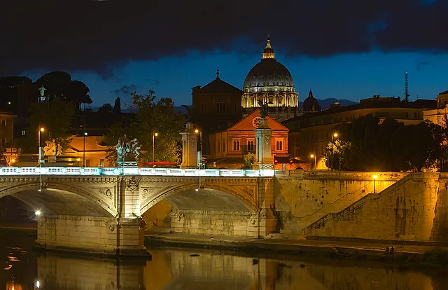 Dusk over the Tiber with Ponte Vittorio Emanuele II in the foreground and the dome of St Peter's Basilica lit against the evening sky